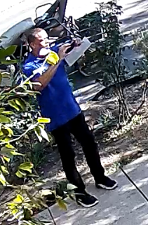Cropped view of blue-shirt official holding phone while facing the property.